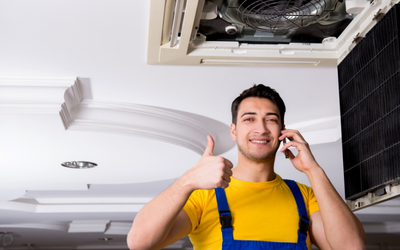 technician giving a thumbs up after repairing an HVAC unit 